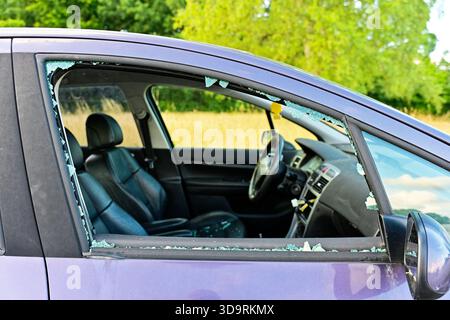 A purple car shows a shattered front passenger side window. Inside, the black leather interior is visible. The damage suggests the vehicle might have Stock Photo
