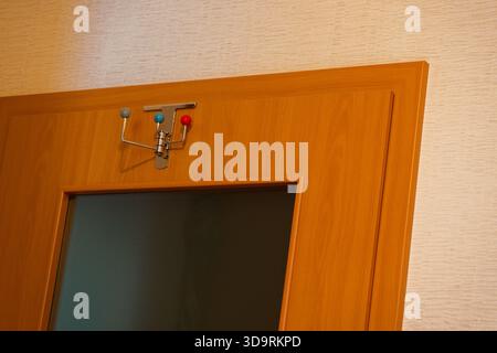 A wooden door with a tinted glass panel features a mounted metal hook rack with colorful ball ends offering a practical and playful spot for hanging i Stock Photo