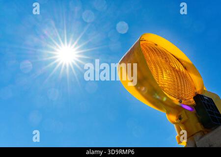 Another yellow Construction site roadworks lamp glows beside the sun. Radiating beams and tiny circular halos dance around the lens, floating against Stock Photo