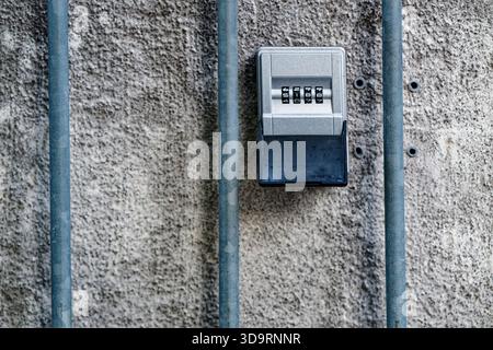 A small key safe is mounted into a solid concrete wall. The numeric panel shows 5 1 8 9 and a gray cover sits below. It provides simple access for ren Stock Photo