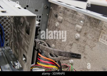 An open metal power supply sits caked in thick dust. Colored wires in black, yellow, orange, red, and green spill from the case, showing age and negle Stock Photo