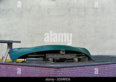 Pink painted brick annex with a rooftop pallet supporting a dark green kayak. Casual storage scene for travel brands, outdoor gear ads, home improveme Stock Photo