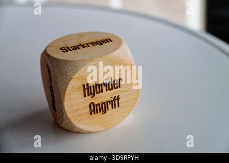 A smooth wooden cube bears the phrase hybrider angriff on the front face suggesting a theme of hybrid attack and modern risk while the rounded shape o Stock Photo