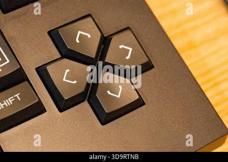 A black keyboard shows the arrow keys clustered in a cross with raised edges and a soft matte finish, the nearby letters fade slightly and the plastic Stock Photo