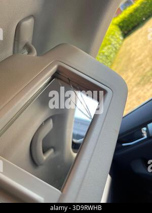 A close up view of a car's sun visor with a cracked mirror. The interior of the car is visible, showing a glimpse of the outside environment through t Stock Photo