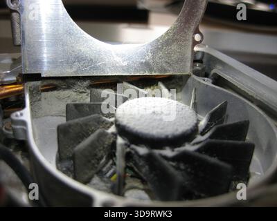 A close up view of a dusty Notebook Laptop fan, showing accumulated dust on the blades and surrounding area. The metallic casing reflects light, highl Stock Photo