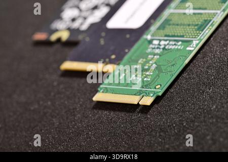 Close-up view of two computer M.2 SSD Harddrive modules on a textured black surface, showcasing their circuit designs and gold connectors. Stock Photo