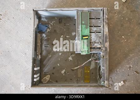 An empty computer case lying on a dusty surface, showing internal components and wiring. The case is metallic with a green component and various slots Stock Photo