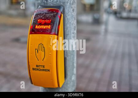 A close-up of a pedestrian traffic signal button with a hand symbol, displaying the message 'Signal kommt' in German, indicating that the signal is ab Stock Photo
