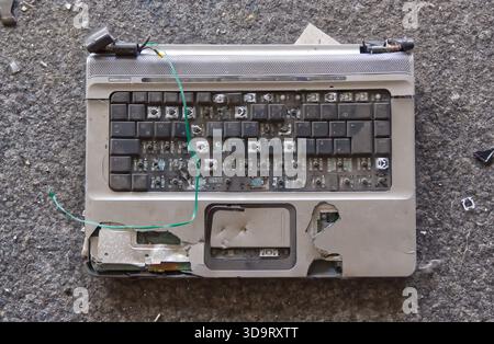 A damaged laptop keyboard with missing keys and exposed internal components. The keyboard is dirty and shows signs of wear and tear, with a green wire Stock Photo