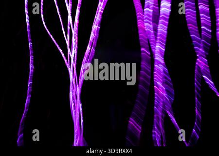 Abstract image featuring vibrant purple light trails against a dark background, creating a sense of movement and depth. Stock Photo