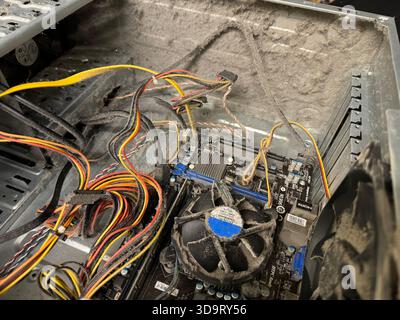 A dusty computer case showing internal components including a motherboard, cables, and a cooling fan. The buildup of dust indicates lack of maintenanc Stock Photo
