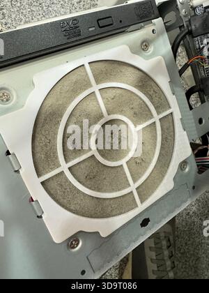 A close-up view of a dusty computer fan filter, showing accumulated dirt and debris. The filter is circular with a grid pattern, mounted on a computer Stock Photo