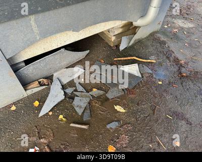 Broken pieces of slate scattered on the ground near a building's foundation. Stock Photo