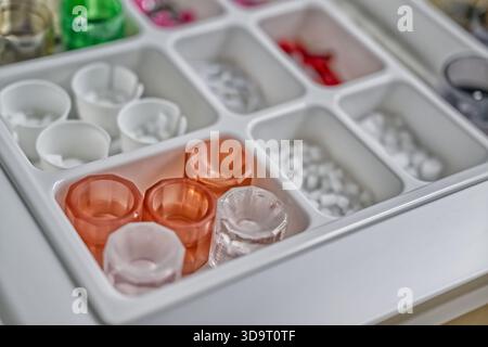 A close-up view of a neatly organized tray containing various small plastic containers and items in different colors, including transparent and colore Stock Photo
