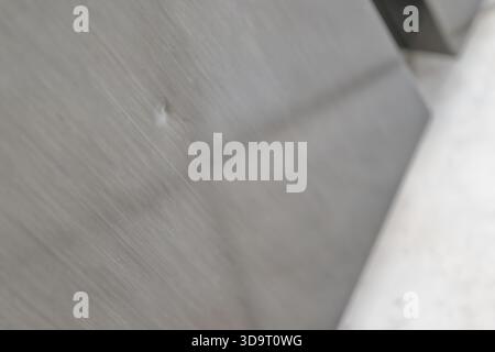 A close-up view of a brushed metal surface showing a small dent and subtle reflections. The background is blurred, emphasizing the texture and finish Stock Photo