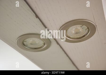 Close-up view of two recessed ceiling lights installed in a white wooden beam, showcasing their circular design and metallic trim. Stock Photo