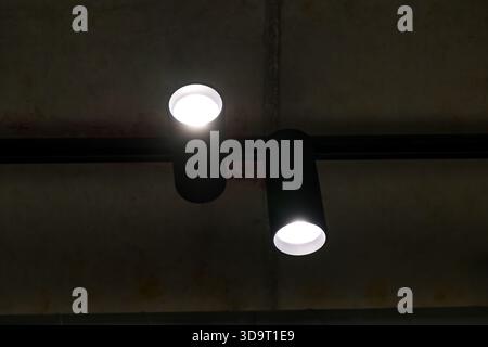 Two modern ceiling lights with a sleek black design, illuminating a dark space. Stock Photo