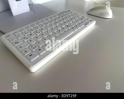 A close-up view of a dental white keyboard and a mouse on a clean, minimalist desk. The keyboard features a compact design with clear keys, and the mo Stock Photo