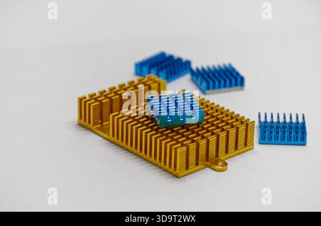 A collection of golden and blue computer heat sinks in various colors, including gold and blue, arranged on a light background. The heat sinks are des Stock Photo