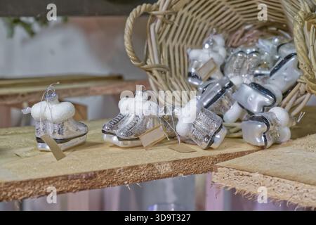 A collection of decorative ice skate ornaments displayed on a wooden surface, with a woven basket in the background. The skates are silver with white Stock Photo