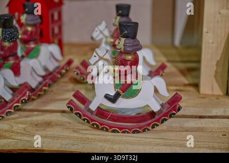 A collection of decorative rocking horse toys featuring soldiers in traditional attire, set against a wooden background. The toys are colorful and whi Stock Photo