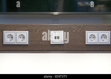 A close-up view of a modern wall with multiple electrical outlets for 230V Power and LAN Network as well Stock Photo
