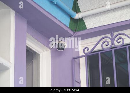Security camera mounted on wall in bright colored building Stock Photo