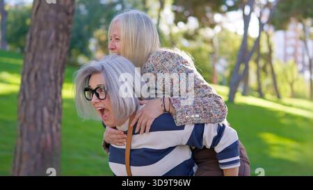 Senior women friends having fun giving a piggyback ride Stock Photo