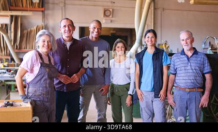 Diverse team of smiling factory workers standing in workshop Stock Photo