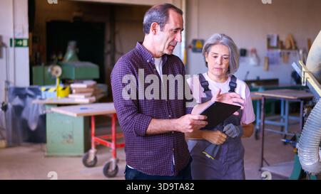 Senior carpenters discussing project using digital tablet in workshop Stock Photo