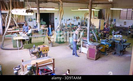 Woodworkers operating machinery in busy carpentry workshop Stock Photo