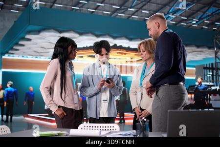 Businesswoman Leading Diverse Exhibitor Team At International Trade Fair Booth Stock Photo