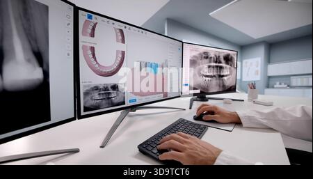 Dentist Examines Dental X-ray Images On Computer Screen With Patient. Stock Photo