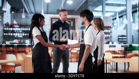 Woman And Man Shake Hands In Restaurant, Celebrating New Partnership. Chefs, Manager Stock Photo
