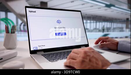 Tech-savvy Office Worker Uploading Data To Cloud Storage On Laptop. Stock Photo