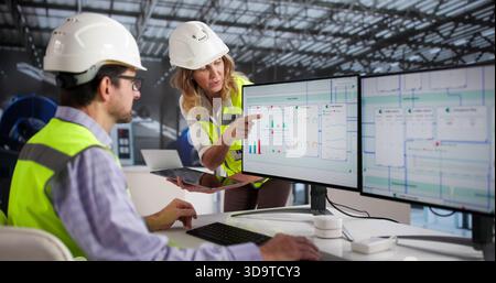 Man And Woman Operating Gas Turbine At Power Plant Facility. Stock Photo