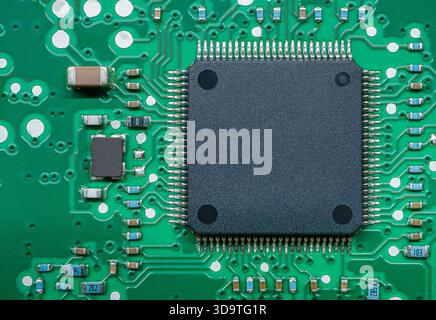 Close-up of a green printed circuit board (PCB) featuring a large black integrated circuit surrounded by components. Stock Photo