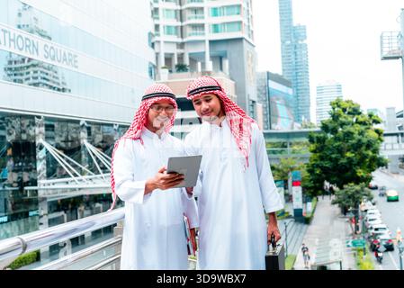 Arab team hold digital tablet uae union teamwork people. Digital marketing arab group of people using smart tablet discuss modern muslim UAE city. Ent Stock Photo