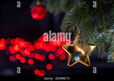 A Christmas background with ornaments hanging on a pine tree and lights in the dark background. Stock Photo