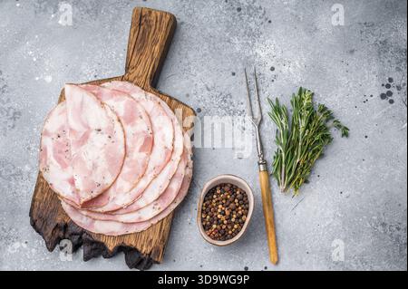 Traditional deli meat (Pancetta) and serving fork on a minimal grey background, perfect for a clean menu design Stock Photo