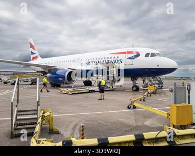 A British Airways jet airliner being serviced by ground operations staff, being refuelled, with cargo & suitcases being loaded, Belfast International Stock Photo