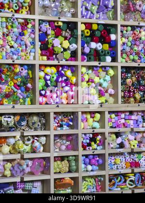 Creative and colorful assortment of craft beads and supplies organized in wooden shelf with many compartments. This vibrant collection inspires hobby Stock Photo