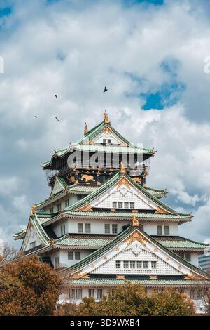 Scenic and historic view of Osaka Castle with bird flying around under dramatic sky in Japan Stock Photo