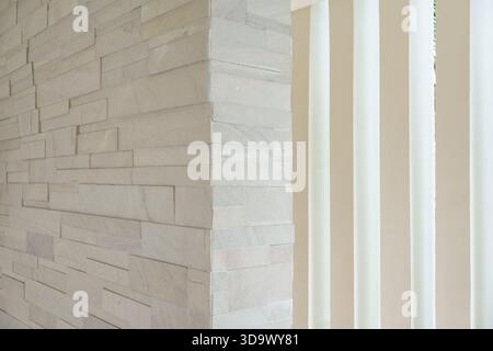 Modern corner of stacked stone wall with modern vertical white panel background Stock Photo