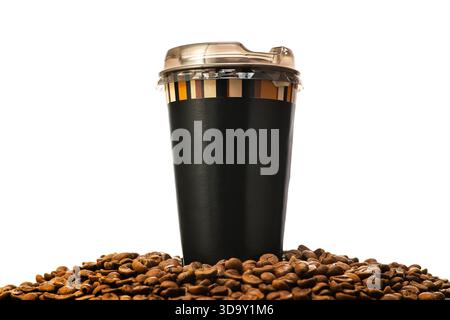 A black coffee cup with a lid sits on top of a pile of coffee beans. The cup is made of plastic and has a clear lid. The coffee beans are scattered ar Stock Photo
