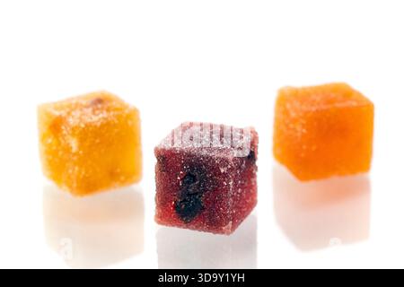 Three different colored cubes of marmalade candy are shown on a white background. The cubes are of different colors and sizes, and they appear to be m Stock Photo