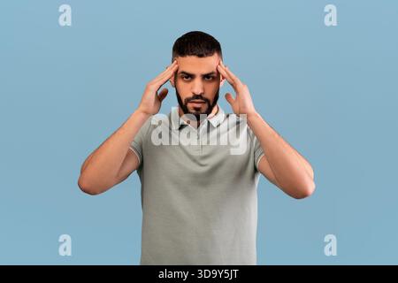 Man Experiencing Stress While Standing Against a Blue Background in a Neutral Pose During Daytime Stock Photo