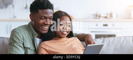 Couple Enjoying Time Together While Using a Tablet in a Bright Kitchen Setting Stock Photo