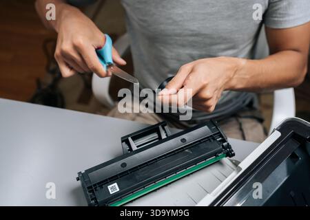 Close-up of person performing regular maintenance on laser printer, checking internal components and replacing an empty toner cartridge in home office Stock Photo